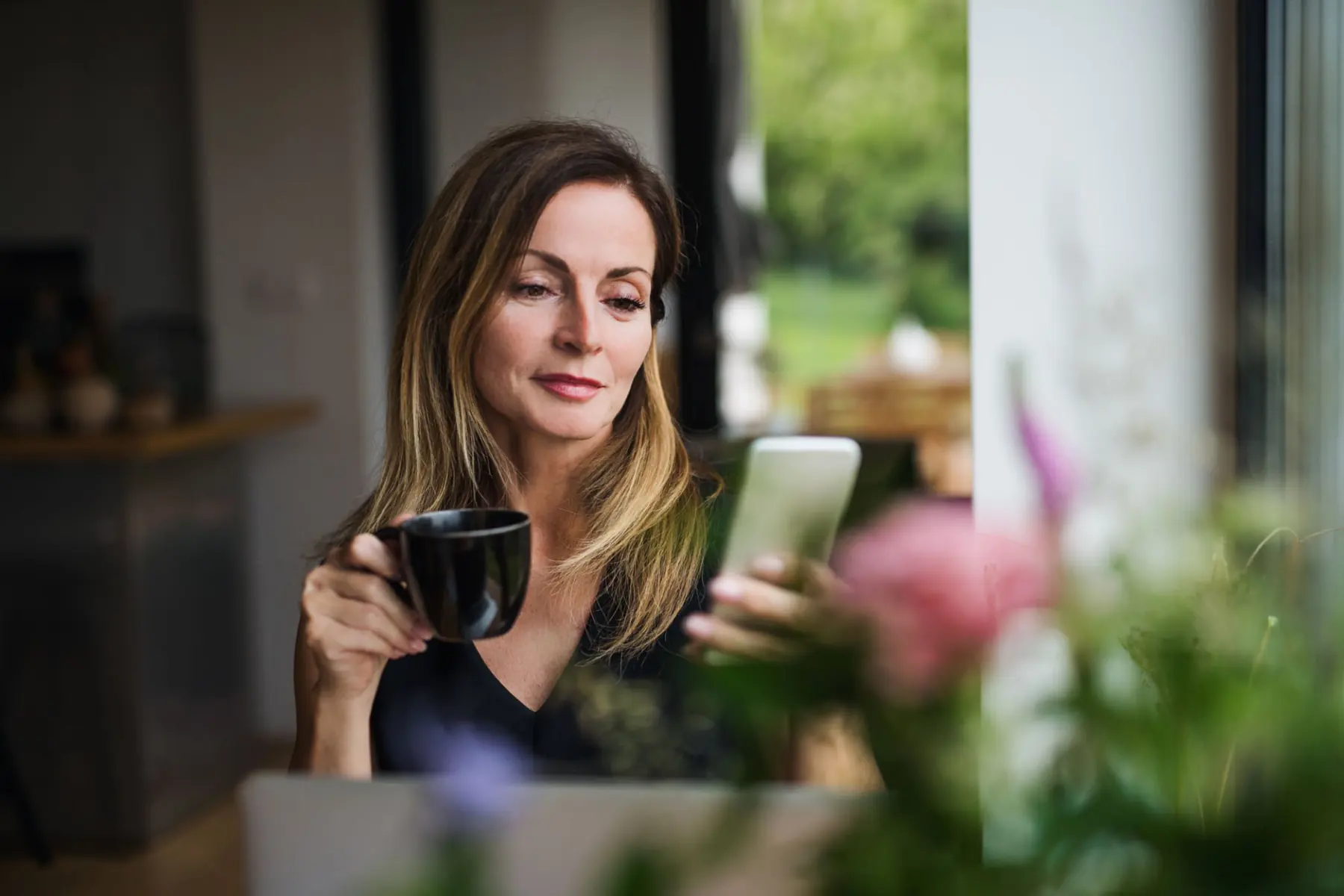A woman choosing her test on her phone over morning coffee at home