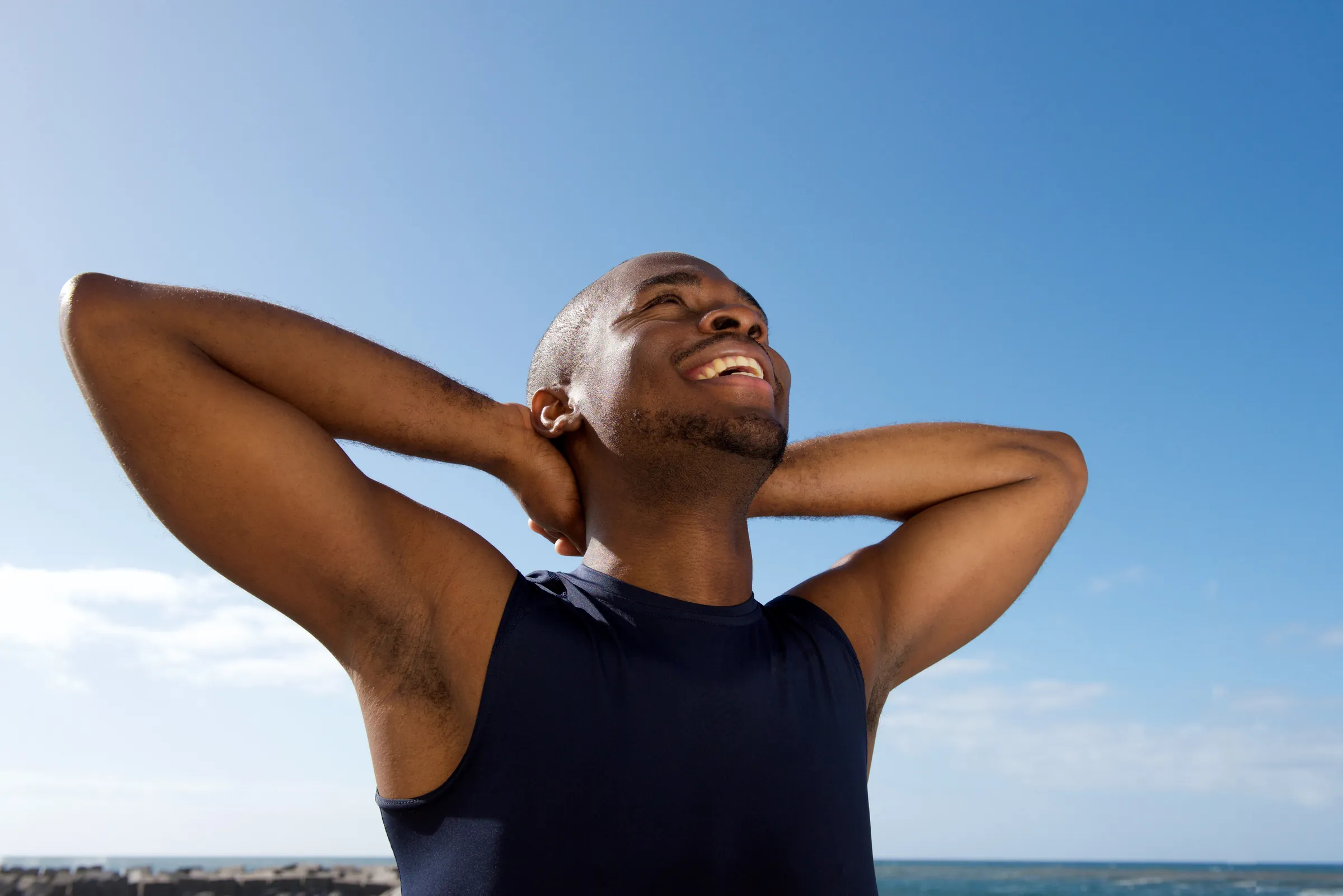 A man relaxing outdoors with his hands behind his head, at ease